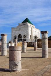 Image du Maroc Professionnelle de  Le tombeau du plus populaire des sultans du Maroc, Mohammed V, père de l’indépendance repose ici dans cette  demeure bâtie en marbre blanc et couronnée par un toit pyramidale orna de tuiles vertes, symbole de la royauté. Sa construction a nécessita une dizaine d’année, au premier plan  les colonnes de l’esplanade de la Mosquée Hassan à Rabat, Jeudi 1er Mars 2007. (Photo / Abdeljalil Bounhar)
